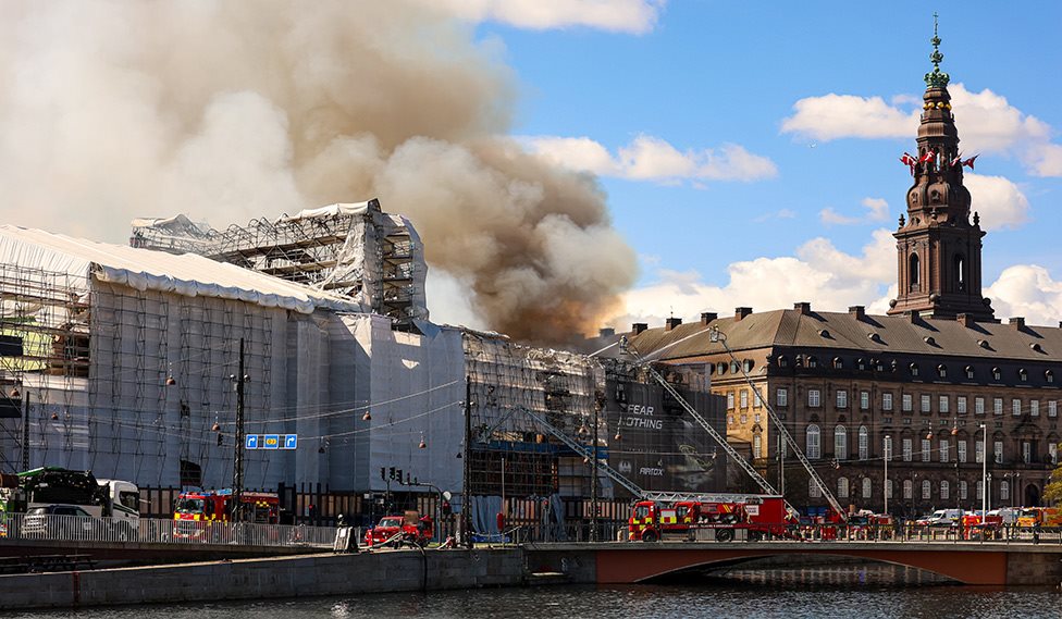 Børsen med sort røg der stiger op og stigebrandbiler som sprøjter vand på Børsen.